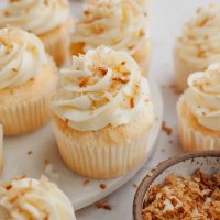 Several coconut cupcakes topped with toasted coconut.