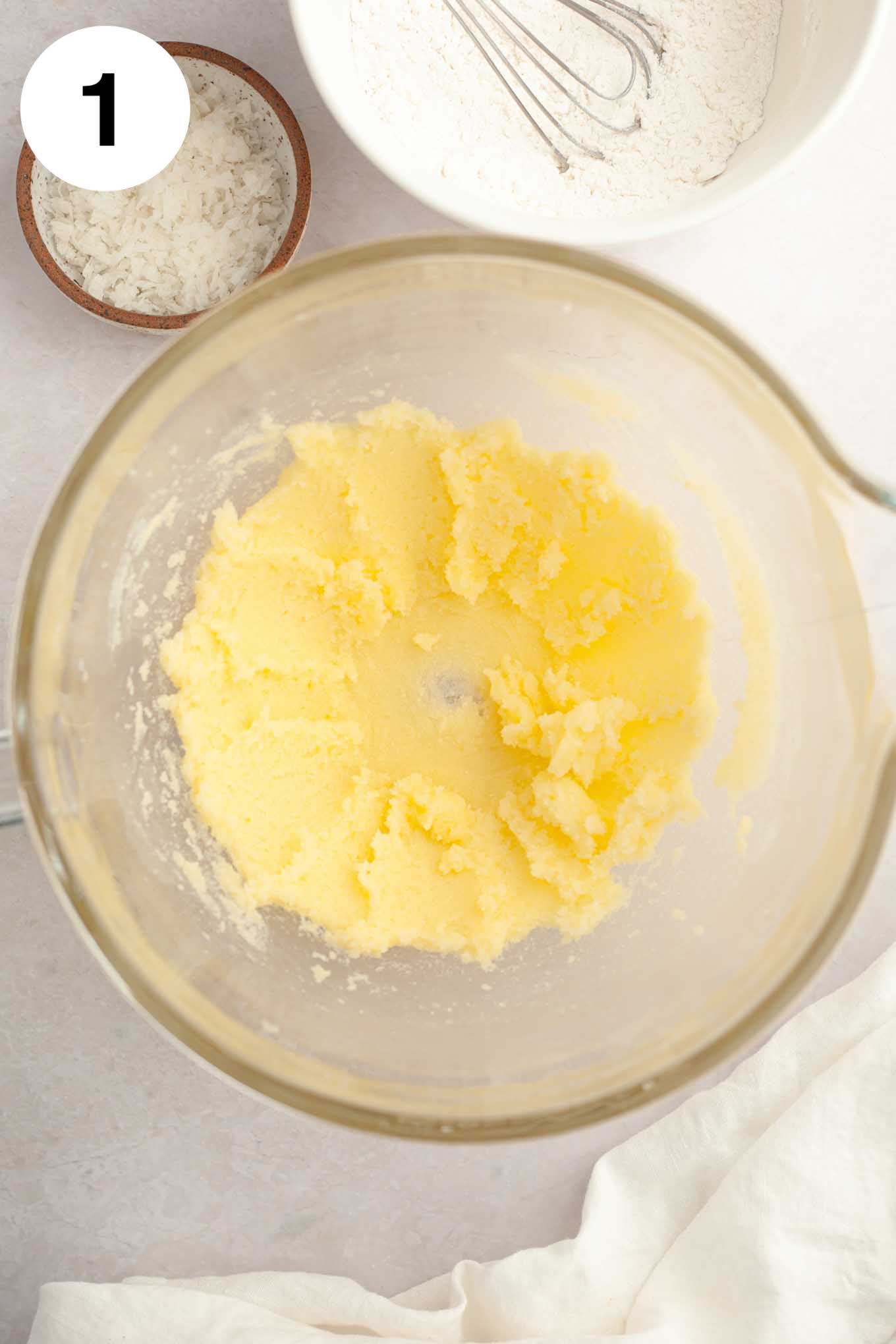 An overhead view of creamed butter and sugar in a glass mixing bowl. 