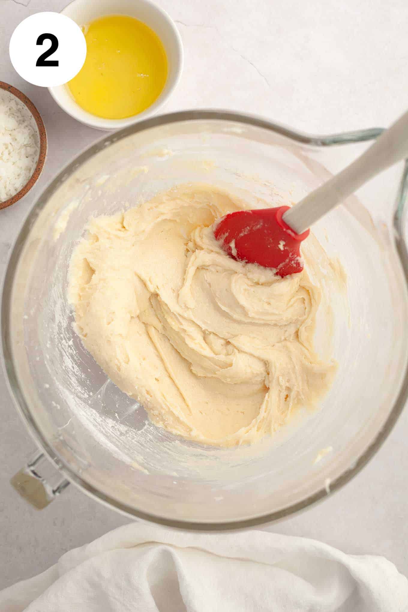 An overhead view of coconut cupcake batter in a glass mixing bowl. 