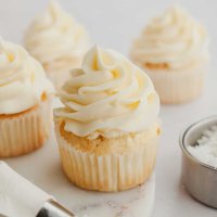 Several coconut cupcakes topped with coconut frosting.