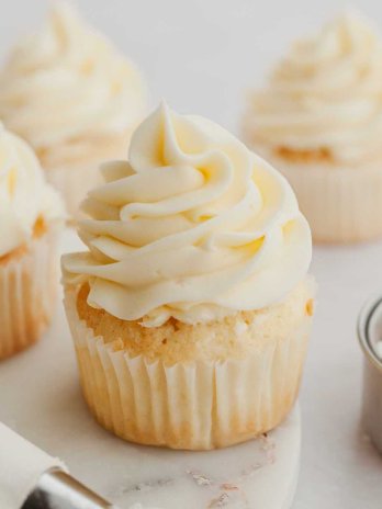 Several coconut cupcakes topped with coconut frosting.