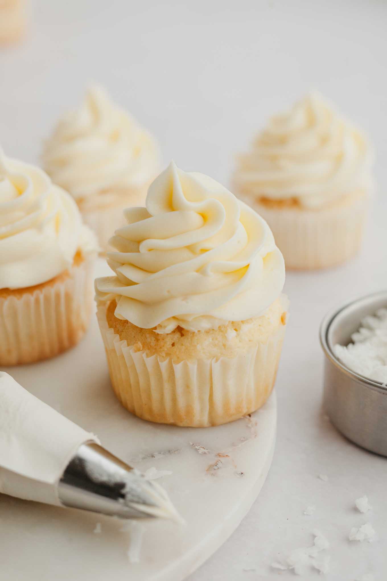 Several cupcakes topped with coconut frosting.