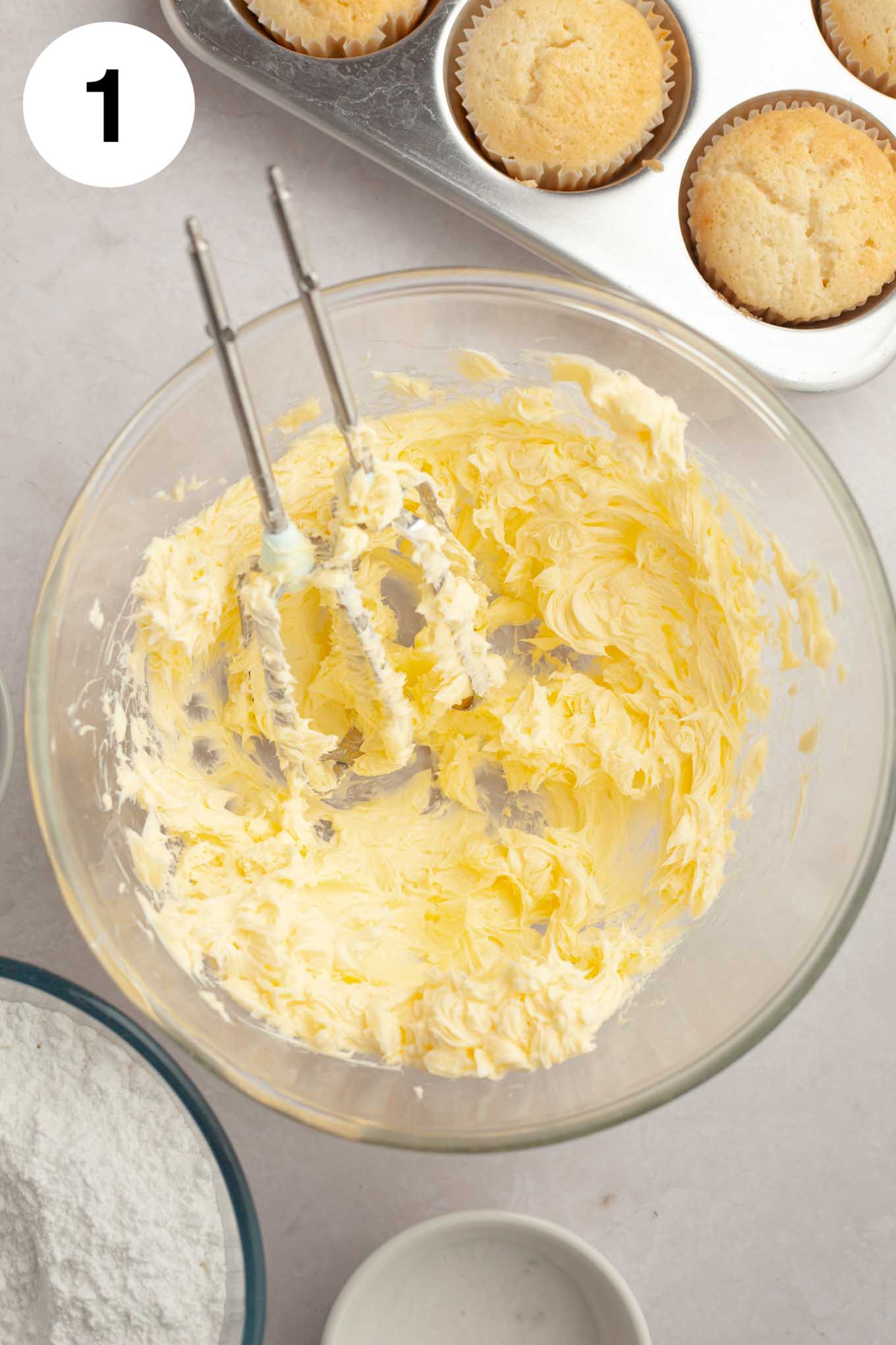 A glass mixing bowl with butter that's been mixed until smooth.