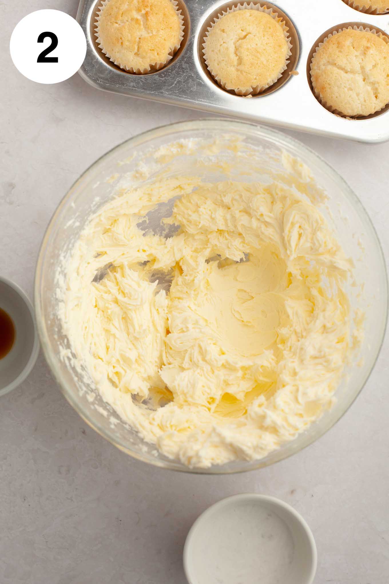 Butter and powdered sugar mixed together in a glass mixing bowl.