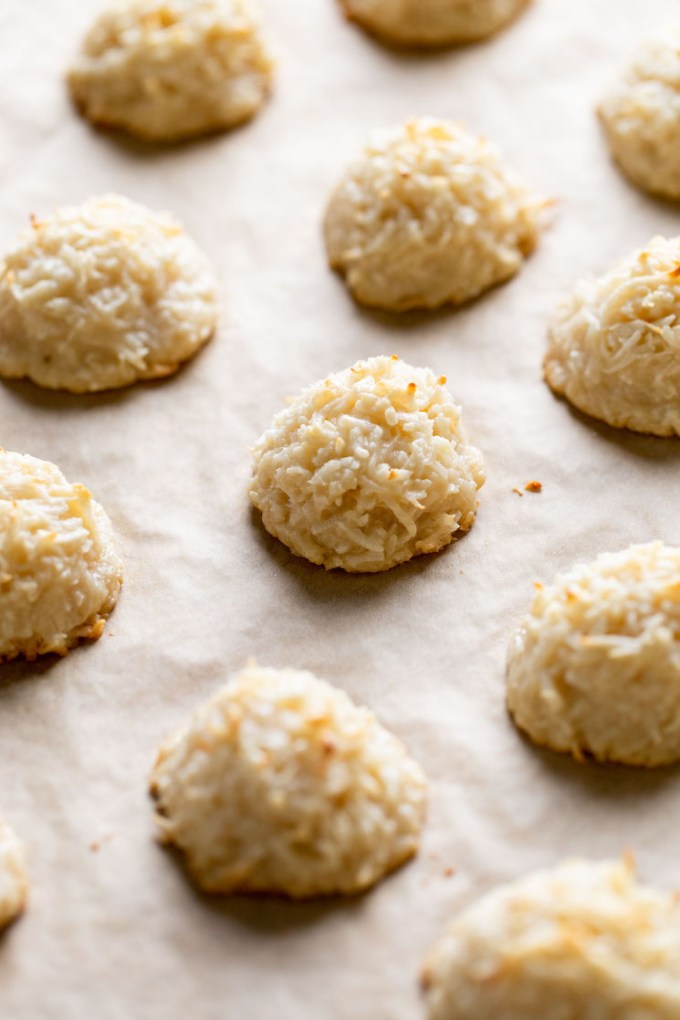 Baked coconut macaroons on a parchment paper-lined baking sheet.