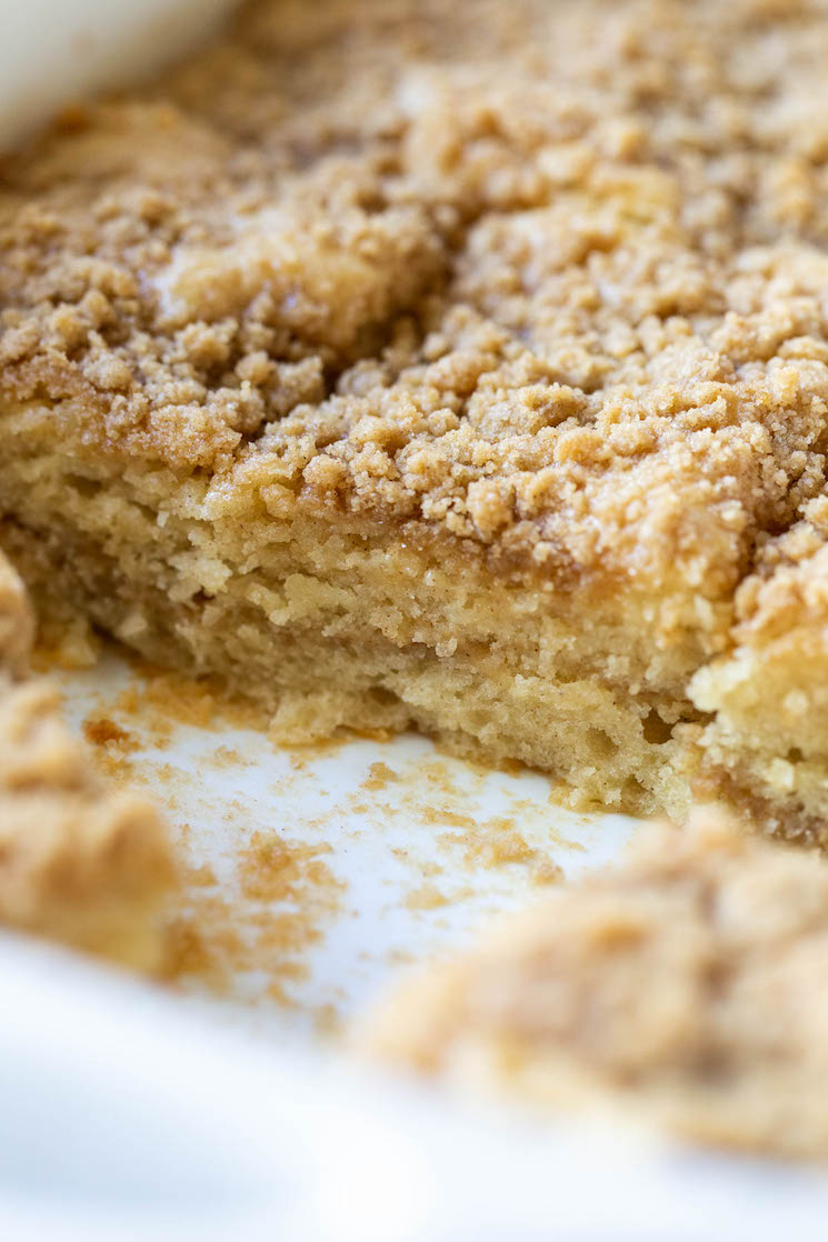 The finished cake still in the baking dish with some pieces removed to show the cake and streusel layers.