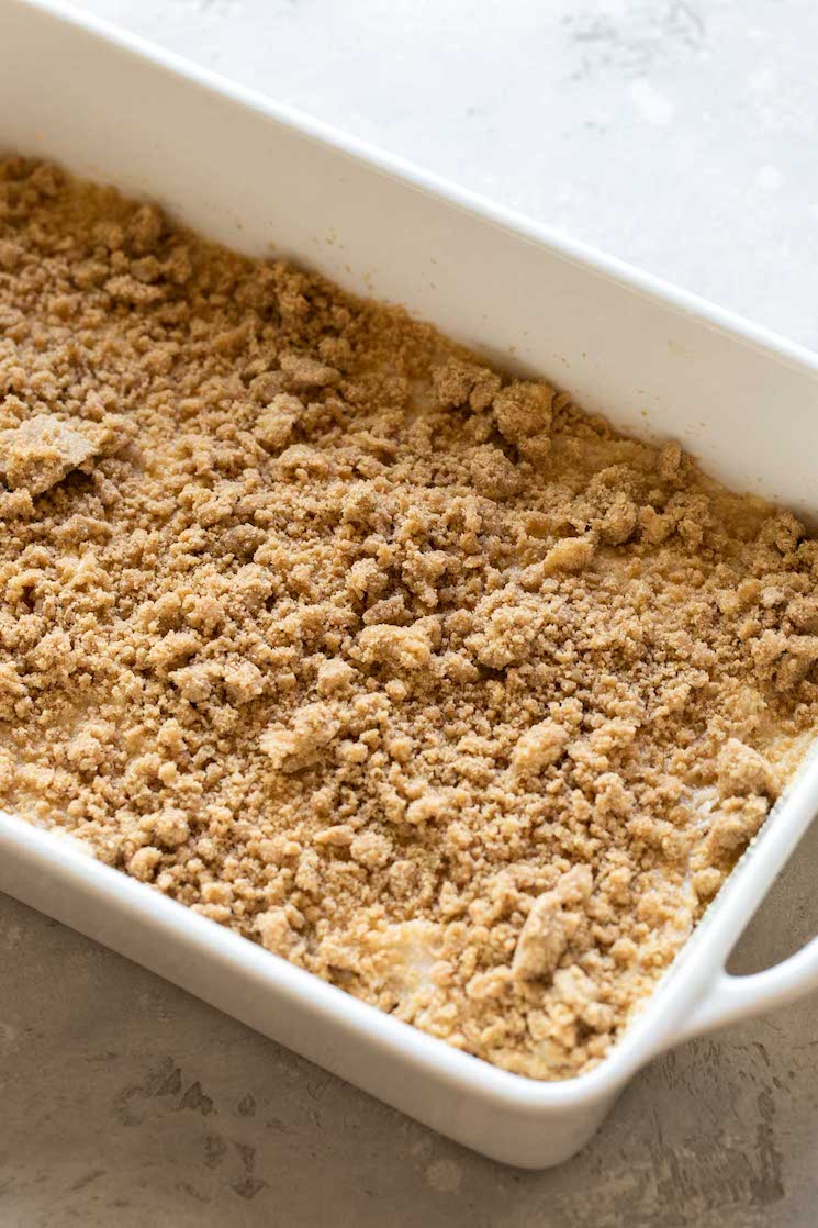 A white baking pan filled with cake batter and topped with a streusel topping.