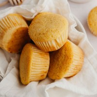 A bowl filled with several cornbread muffins.