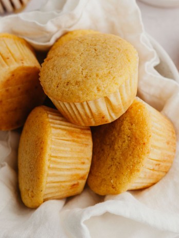 A bowl filled with several cornbread muffins.