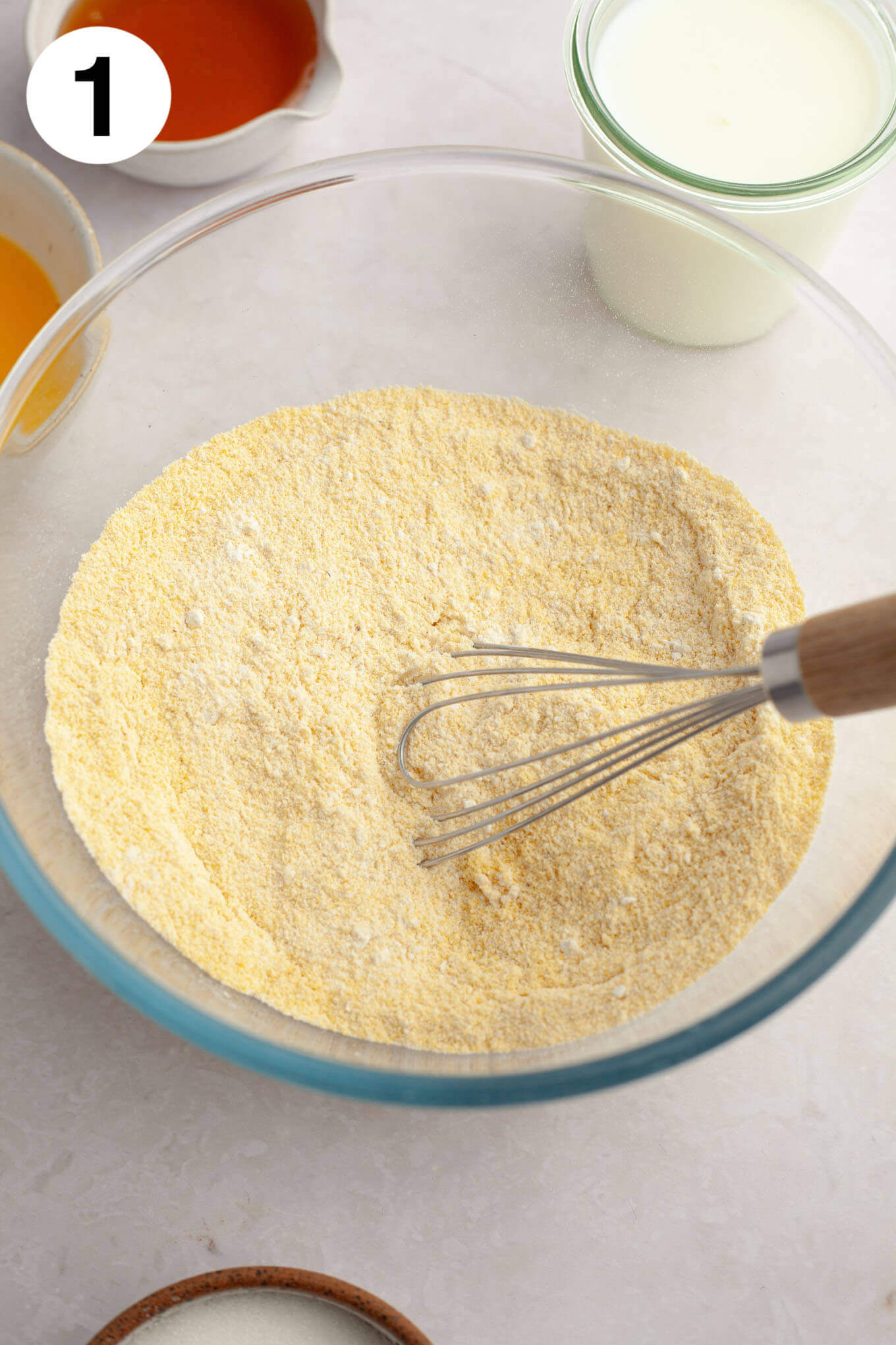 An overhead view of the dry ingredients mixed together in a glass mixing bowl. 