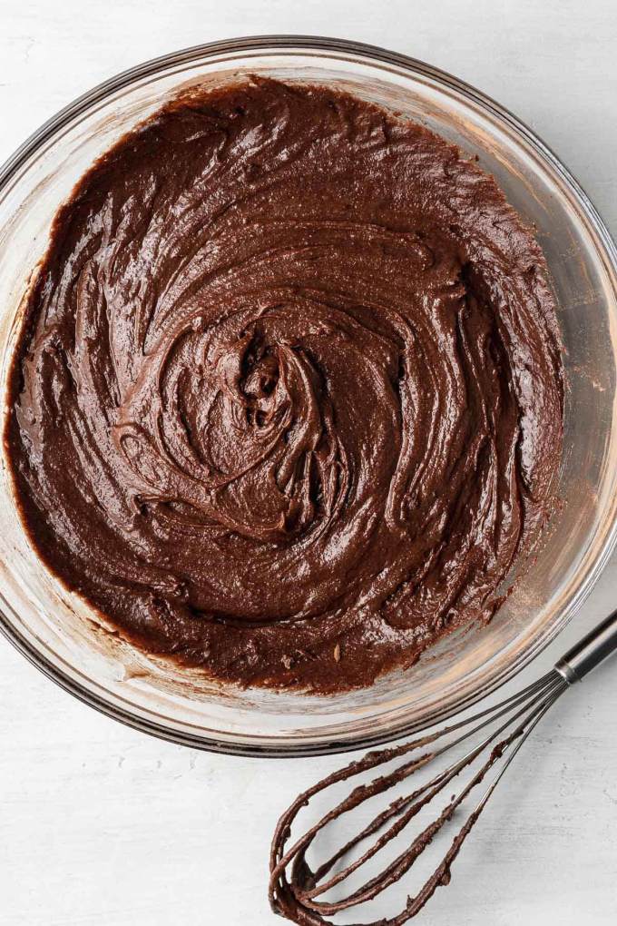 An overhead view of brownie batter mixed together in a glass mixing bowl.