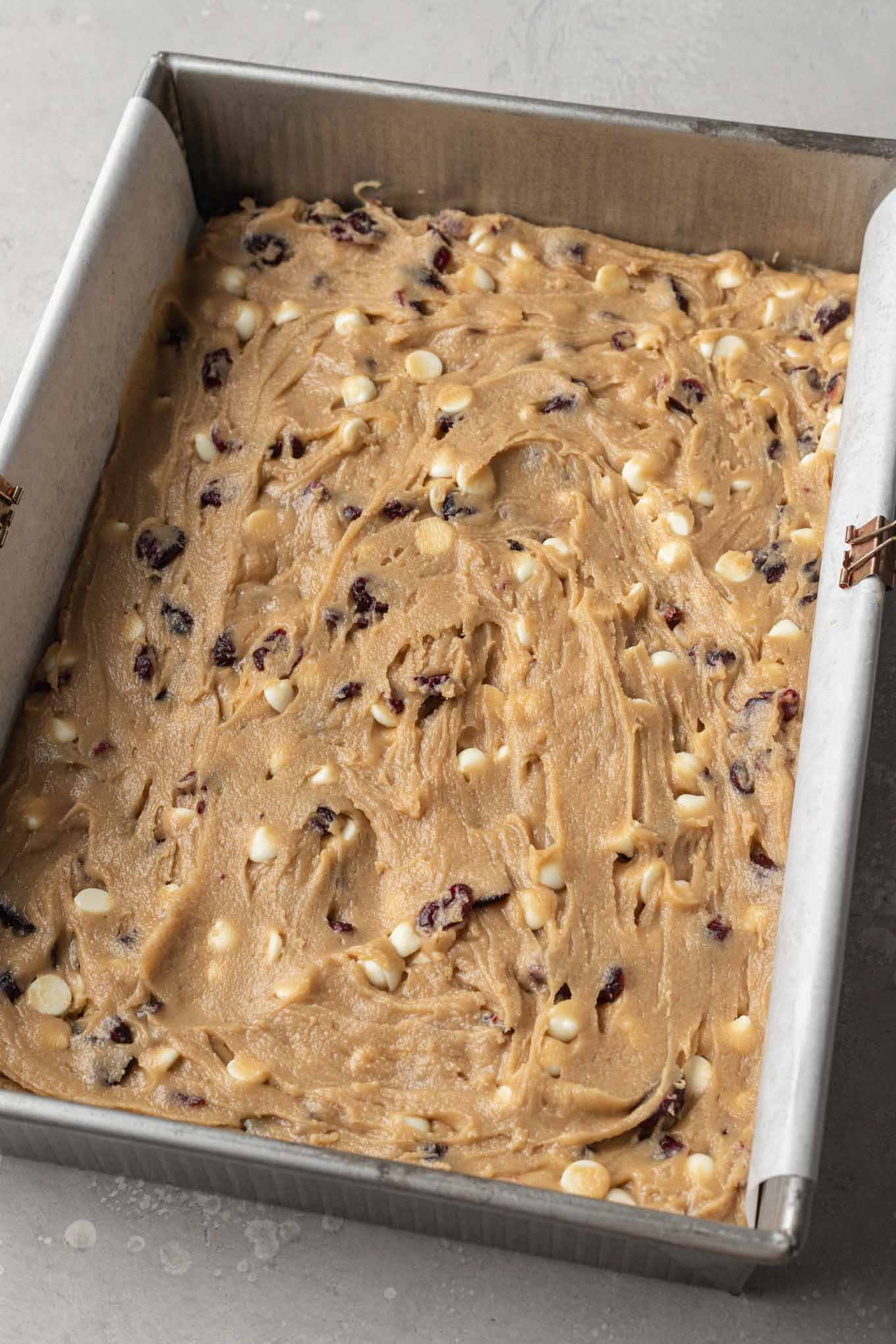 An overhead view of raw cranberry bliss bars in a baking dish. 