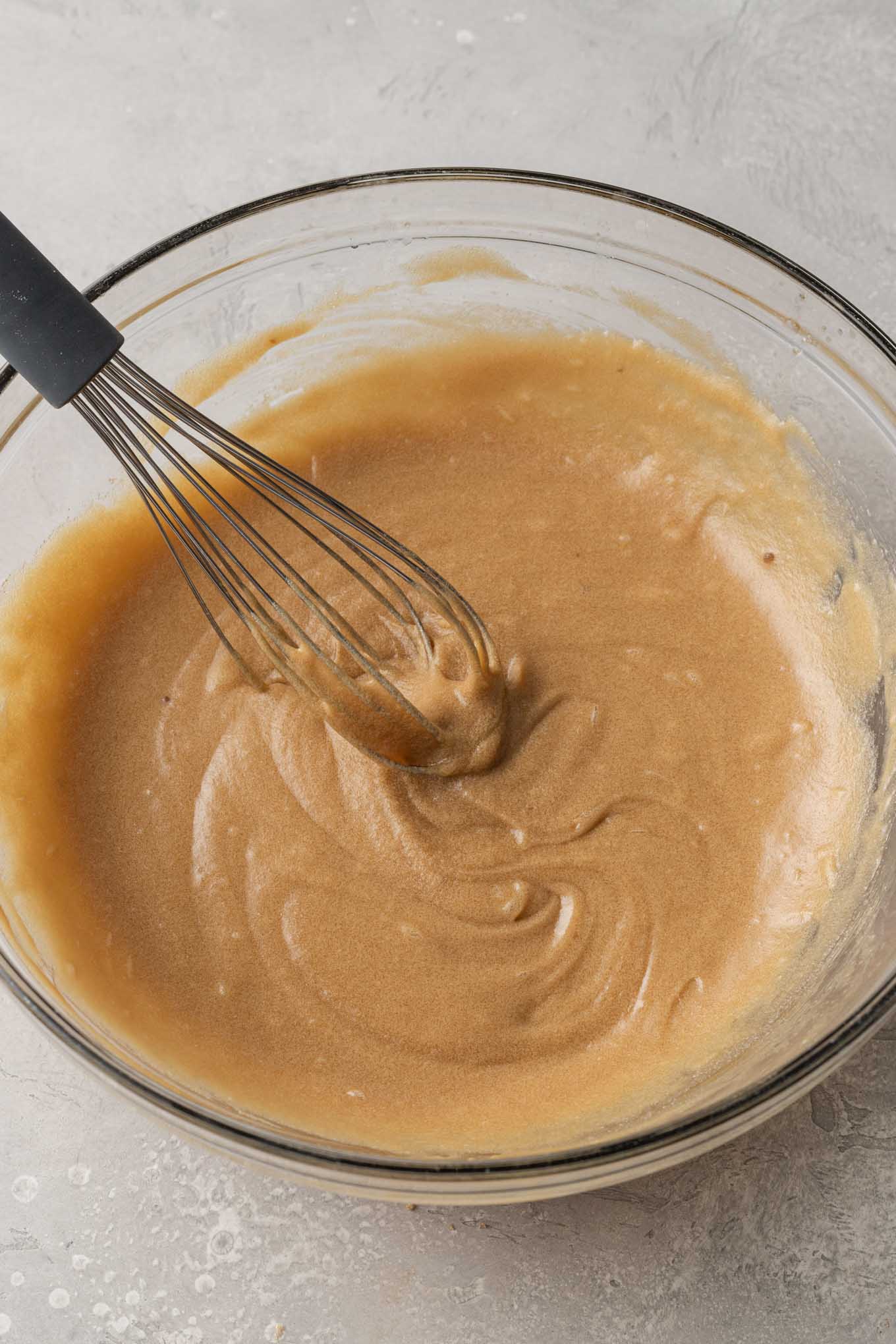 An overhead view of the wet ingredients in a glass mixing bowl. 