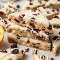 Several iced cranberry bliss bars stacked on top of each other.