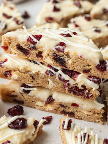 Several iced cranberry bliss bars stacked on top of each other.