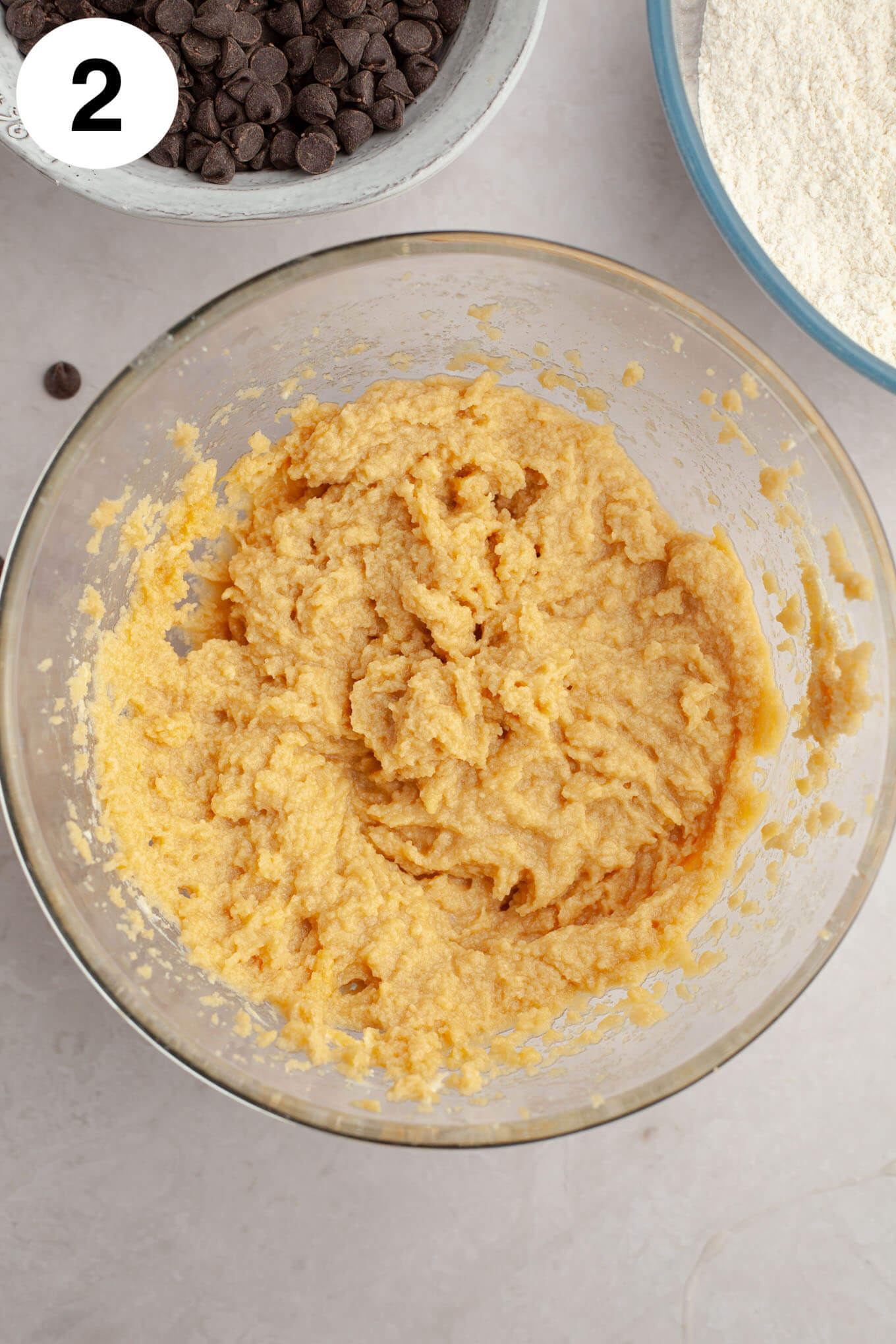 An overhead view of a glass mixing bowl with the wet ingredients mixed together.