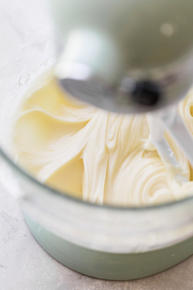 A glass mixing bowl with frosting that has finished mixing showing its smooth texture.