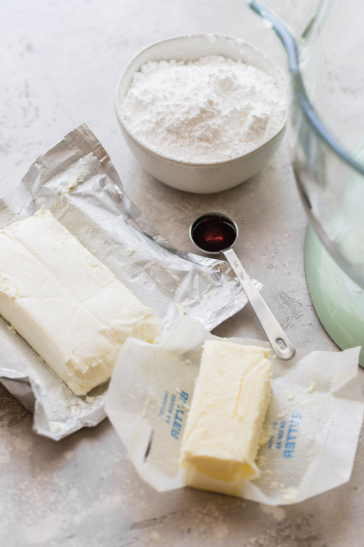 The ingredients needed to make cream cheese frosting laying on a gray surface.