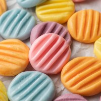 Several pastel cream cheese mints on a piece of parchment paper.