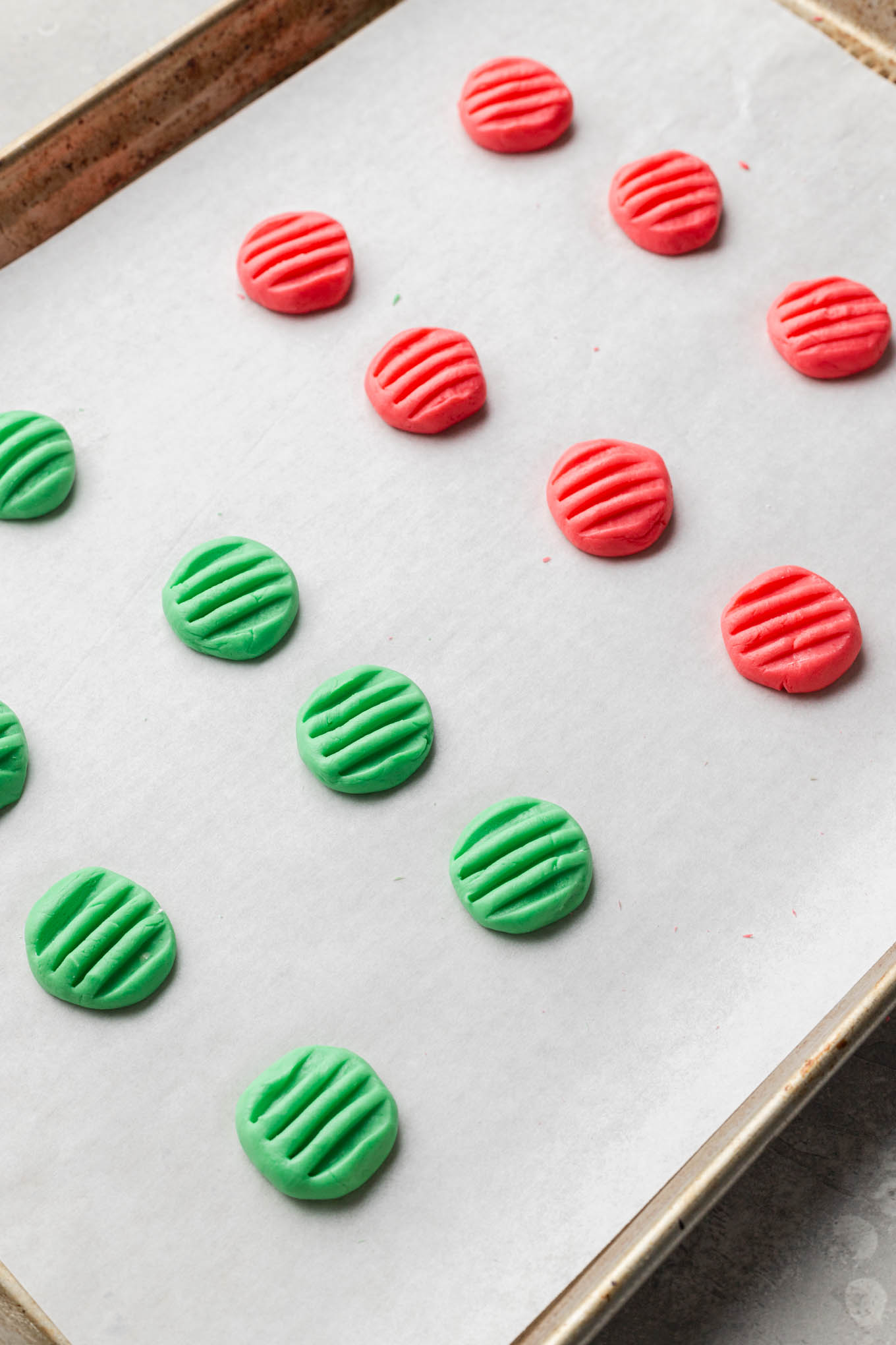 Red and green mints drying on a parchment paper-lined baking sheet. 