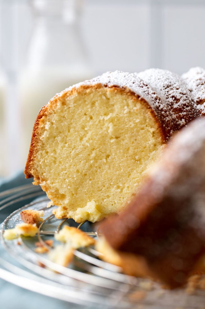 Close up of a sliced pound cake, seen from the side. Milk bottles rest in the background. 