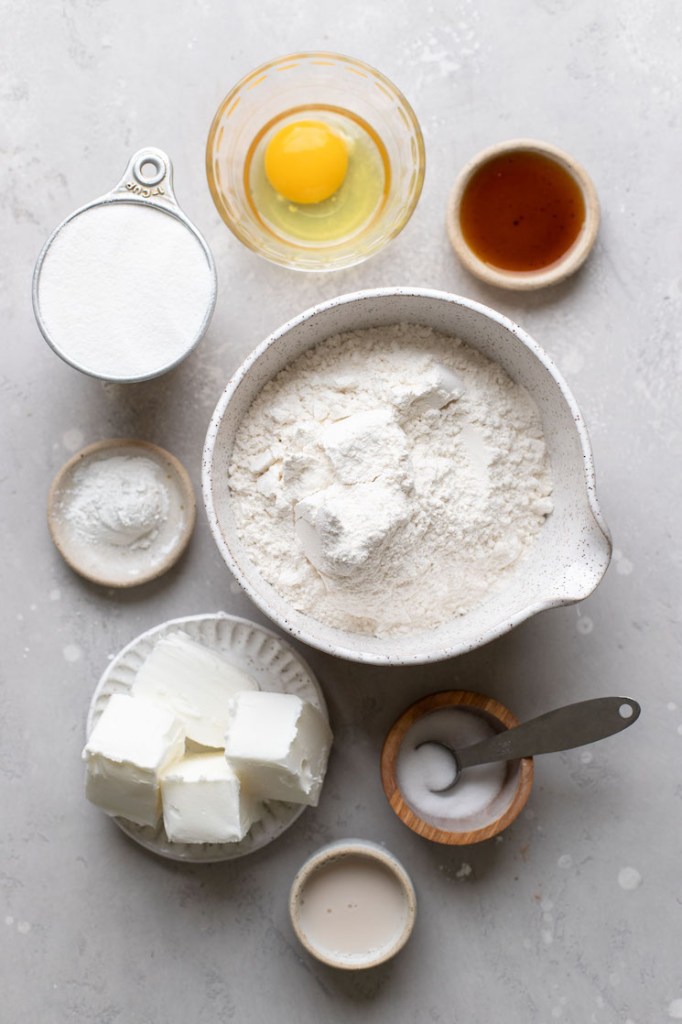 The ingredients needed to make cut-out sugar cookies laid out on a rustic gray surface.