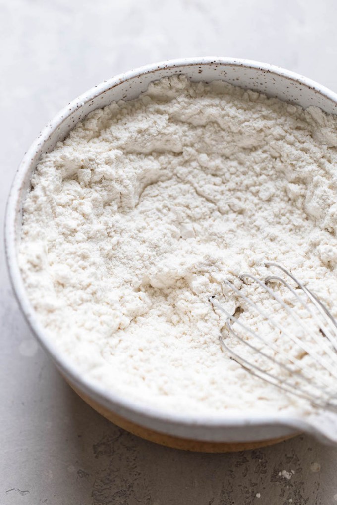 The dry ingredients for cookies in a speckled white bowl.