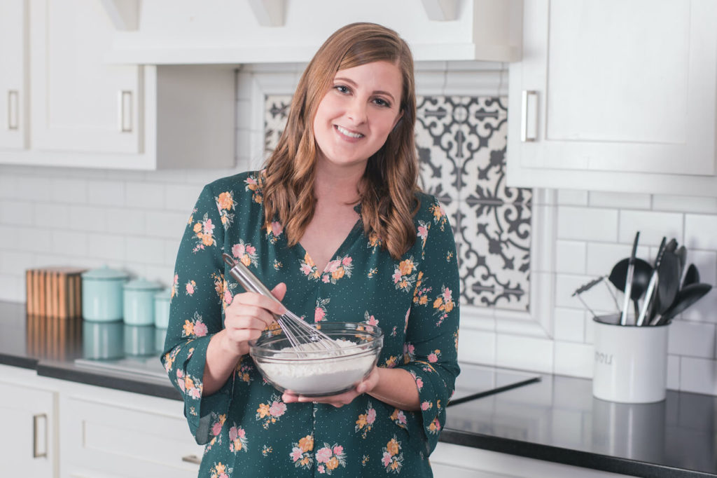 A picture of Danielle in a green shirt in her kitchen.