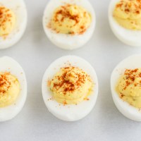 A close-up picture of deviled eggs on a piece of parchment paper.