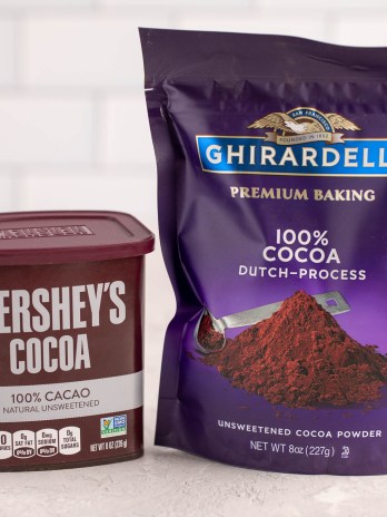 A container of Hershey's natural cocoa powder and a package of Ghirardelli Dutch process cocoa powder sitting next to each other.