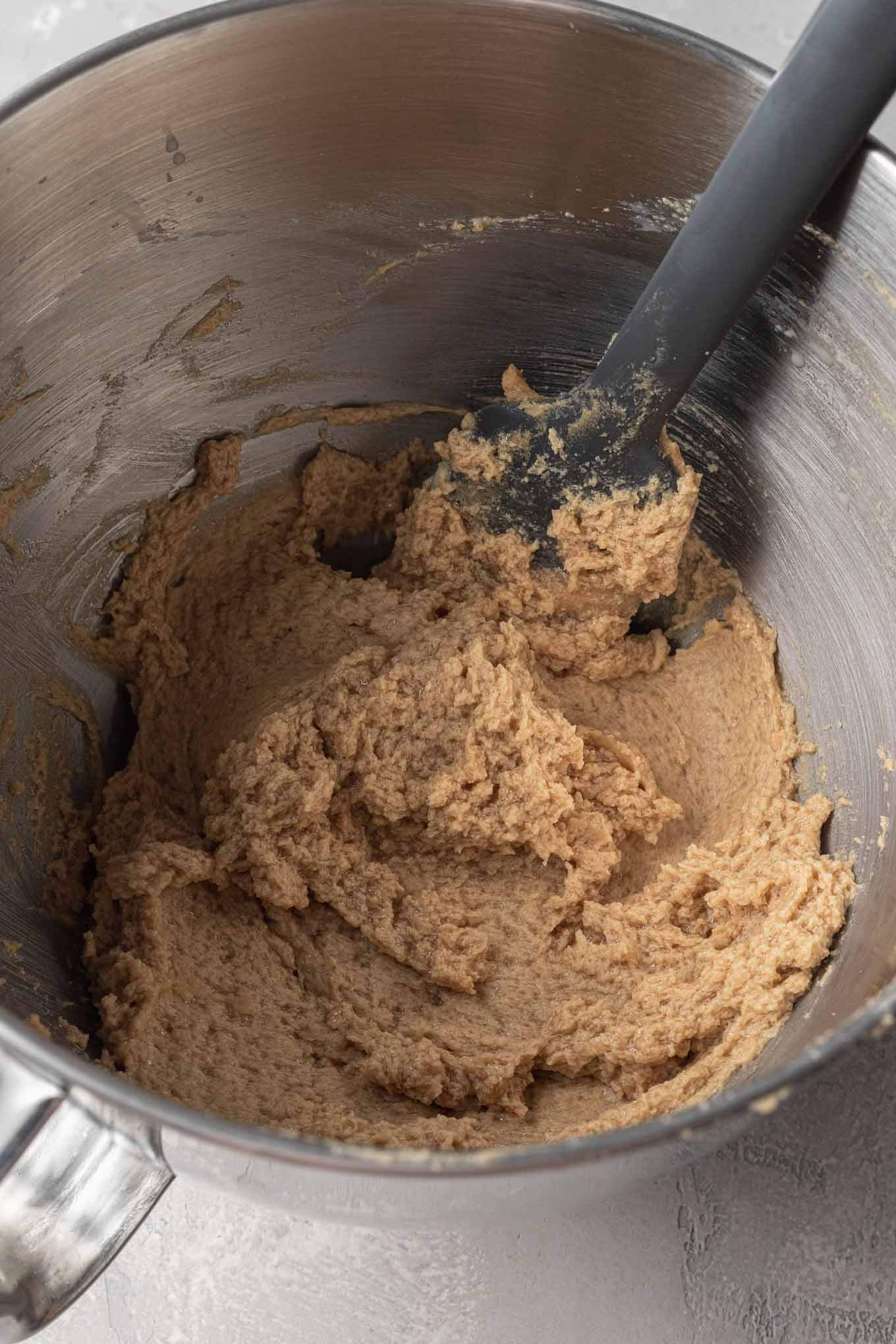 Eggless chocolate chip cookie dough in a metal mixing bowl, with a rubber spatula. 