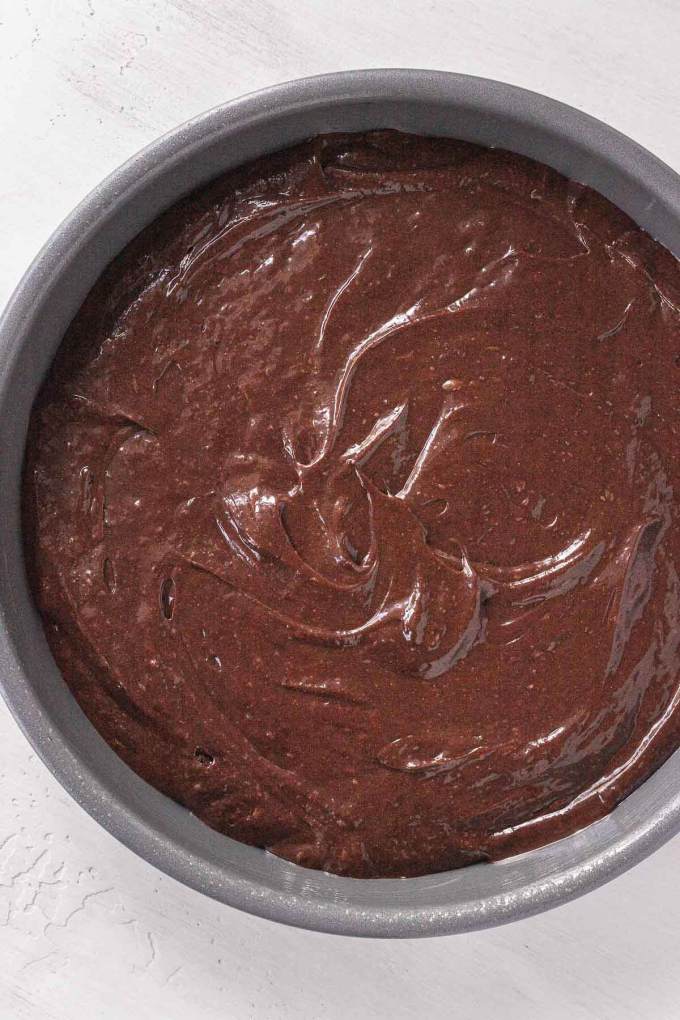 An overhead view of chocolate cake batter in a metal baking tin.