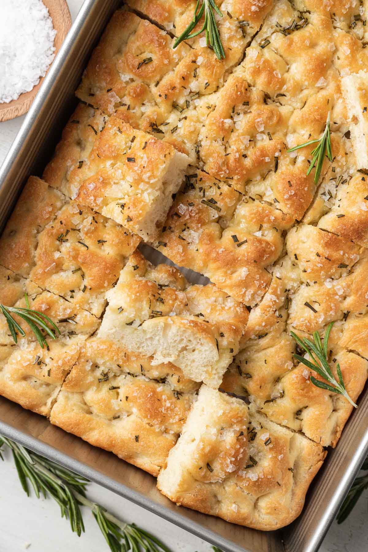 An overhead view of a pan of focaccia bread that's been sliced into pieces.