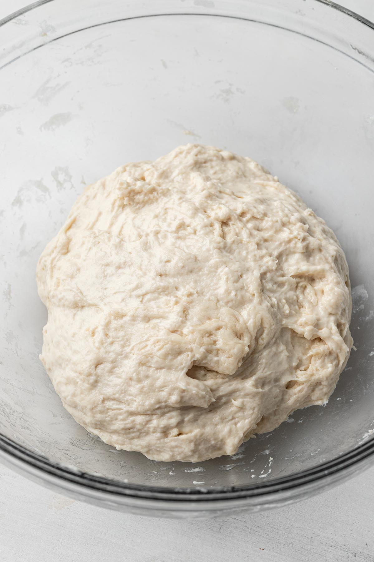 Unkneaded focaccia dough in a glass mixing bowl.