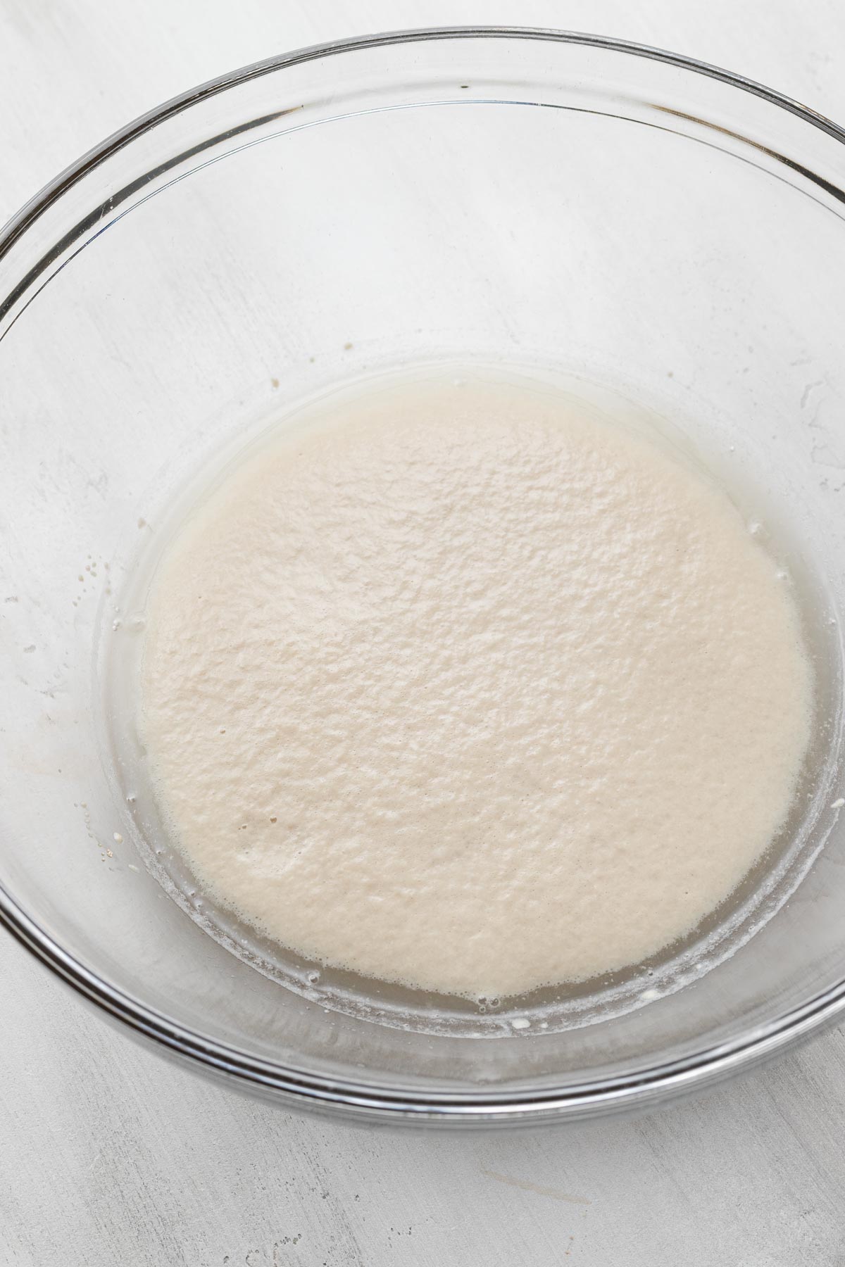 Foamy yeast mixture in a glass mixing bowl.