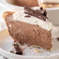 A slice of French silk pie topped with homemade whipped cream and chocolate curls.