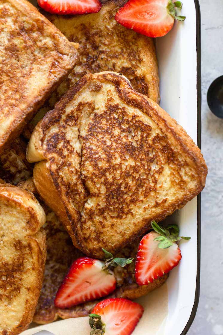 A close up image of French toast in a baking pan topped with halved strawberries.