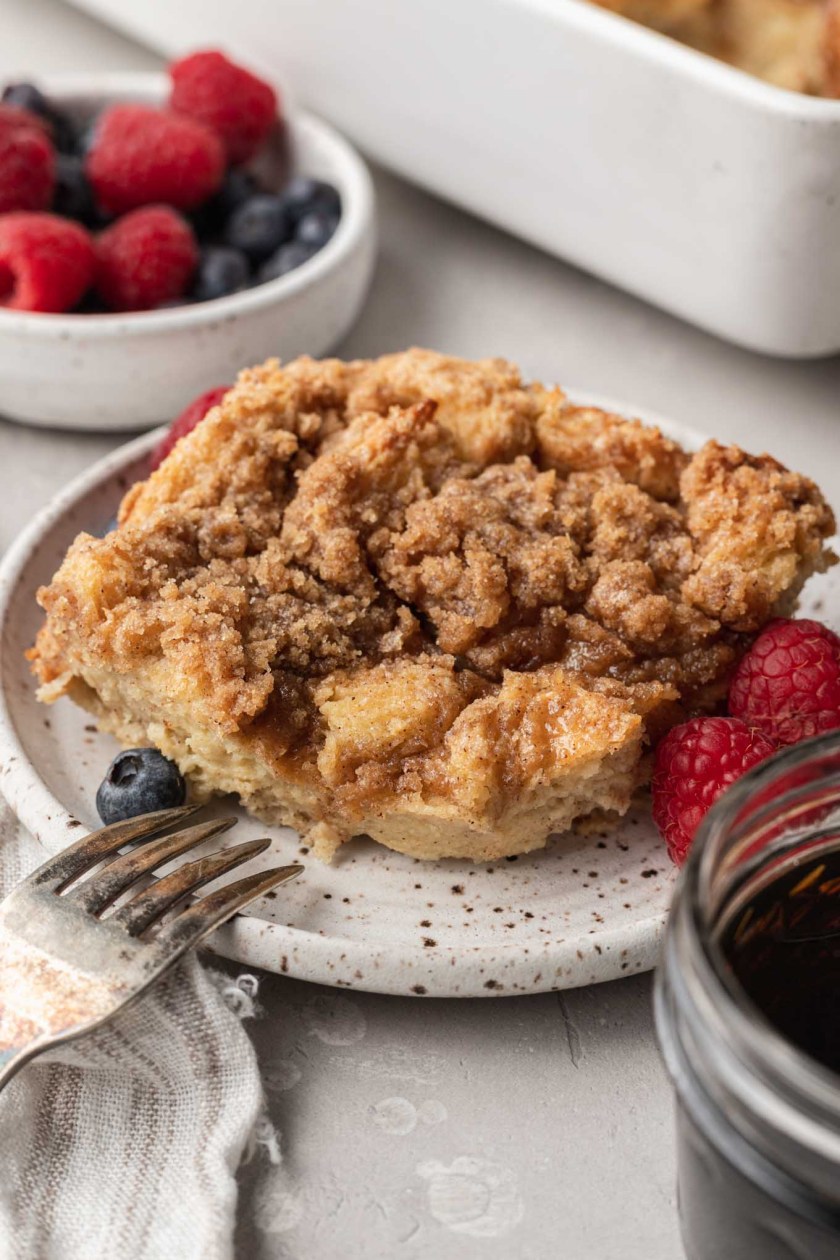 A serving of challah french toast casserole on a small plate with fresh berries. 