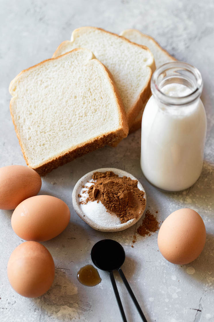 The ingredients needed to make French toast sitting on a rustic gray surface.