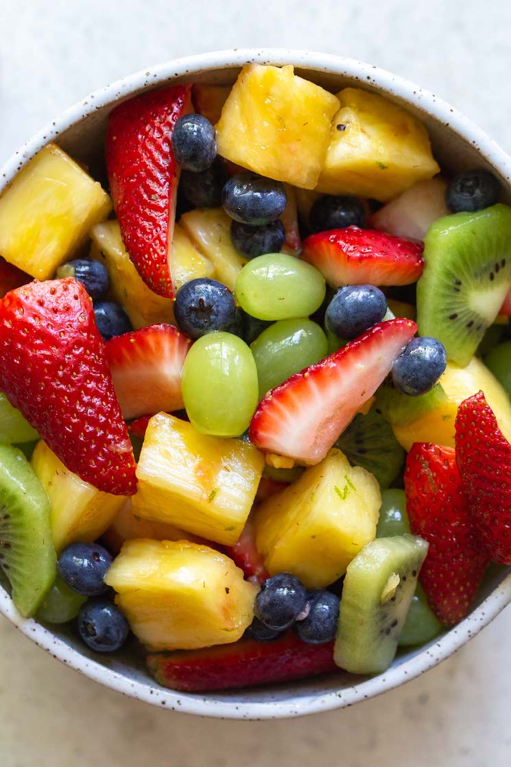 A close up image of fruit salad in a clay bowl.