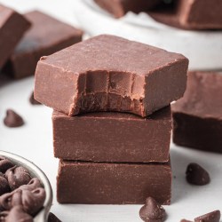 Three pieces of fudge stacked on top of each other. The top piece has a bite taken out of it.