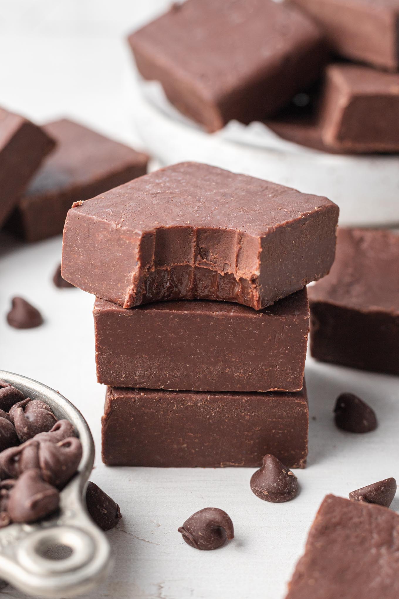 A stack of chocolate fudge slices. The top slice has a bite missing. 