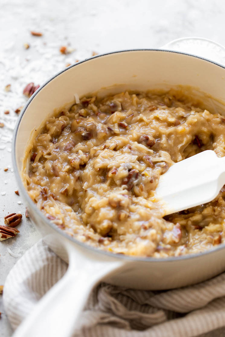 A white pot filled with homemade coconut pecan frosting.