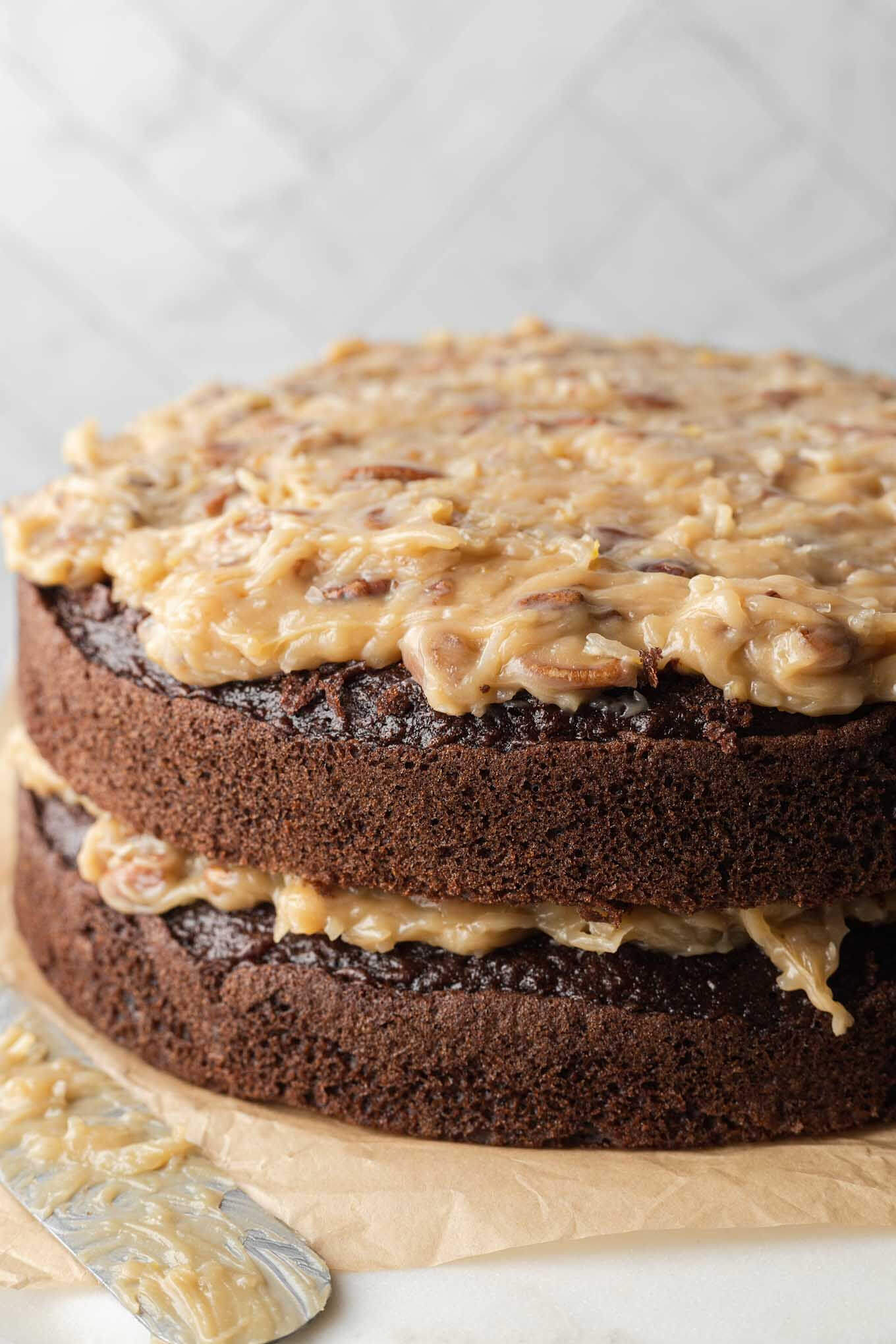 A side view of a layered German chocolate cake with homemade frosting. 