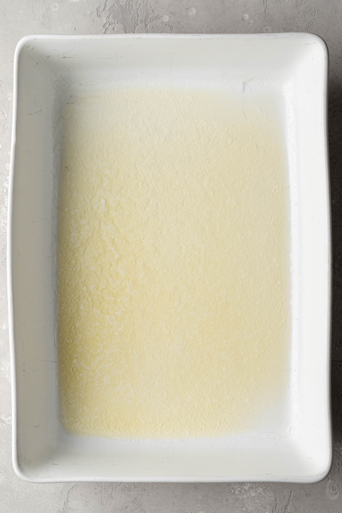 An overhead view of melted butter in a casserole dish. 