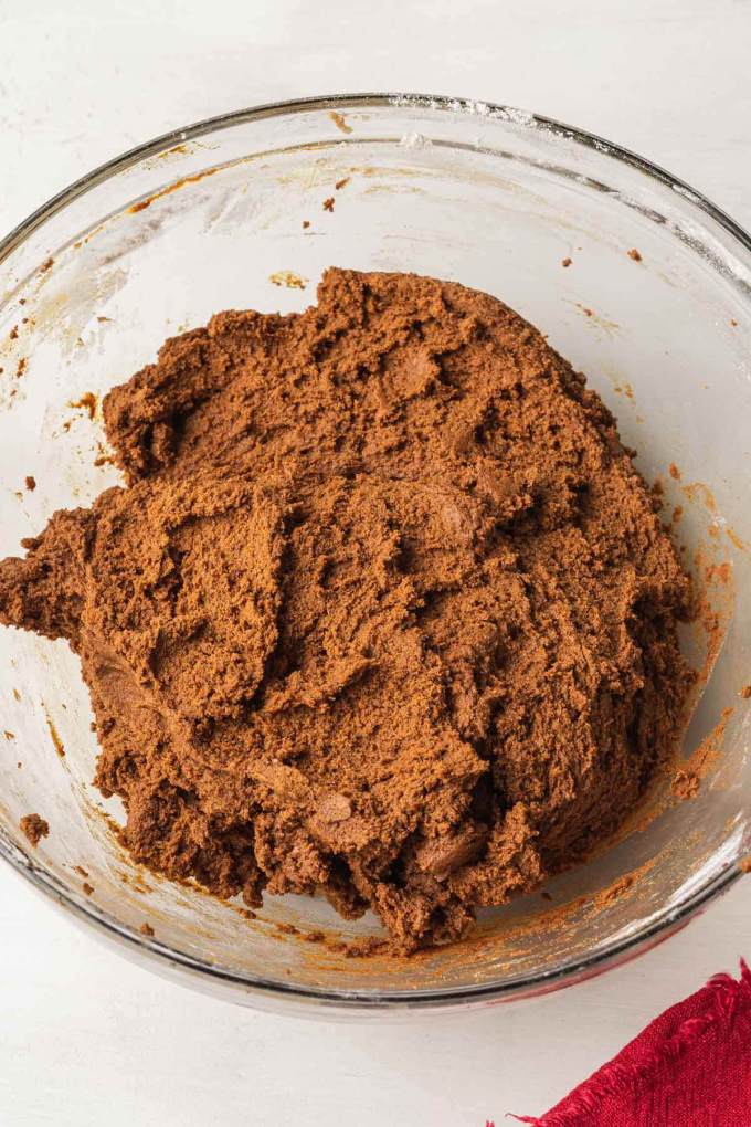 An overhead view of a glass mixing bowl filled with gingerbread cookie dough.