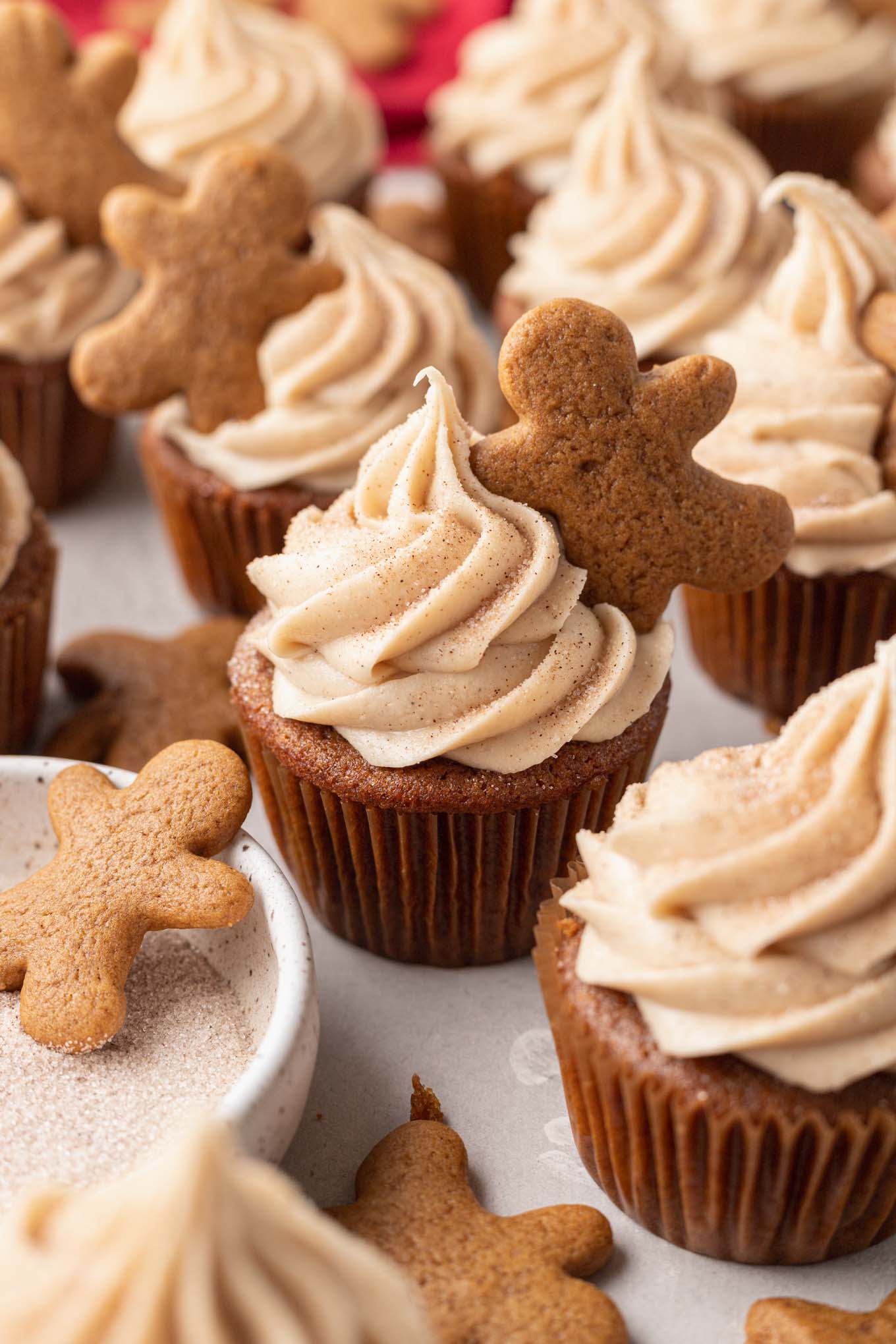 Gingerbread cupcakes piped with cinnamon cream cheese frosting and topped with a mini gingerbread cookie. 