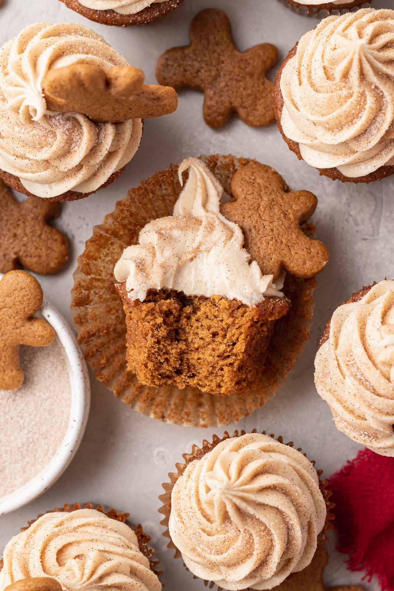 An overhead view of a gingerbread cupcake on its side in a cupcake liner, with a bite missing. 