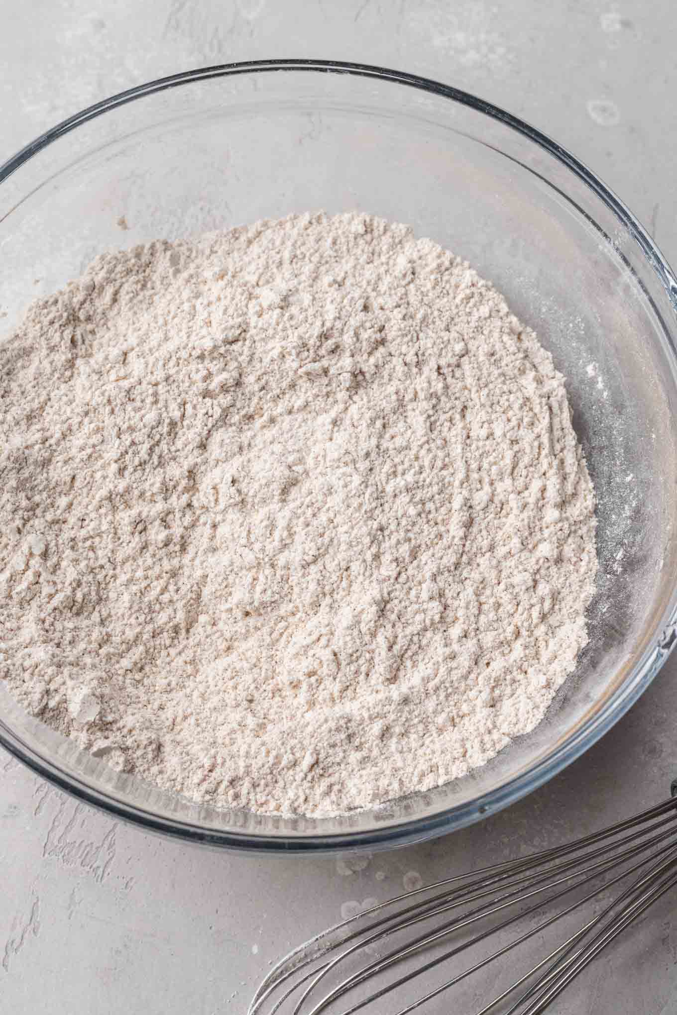 An overhead view of flour and spices in a glass mixing bowl. 