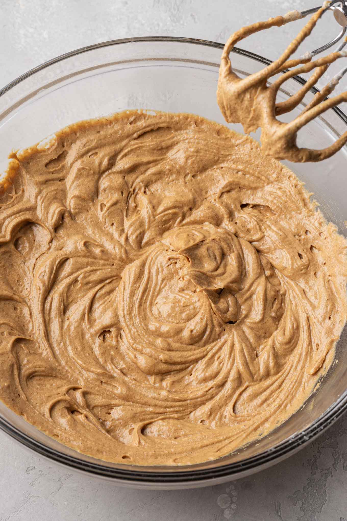 An overhead view of gingerbread cupcake batter in a glass mixing bowl. 